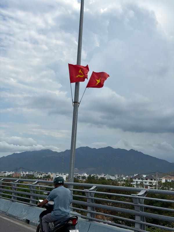 Man in helmet sits near Vietnamese flags in Nha Trang