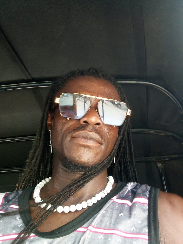 Man takes selfie wearing sunglasses and beaded necklace