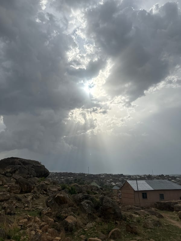 Dramatic sunbeams pierce clouds over Jos cityscape