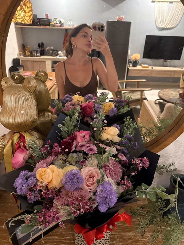 Woman takes selfie, flower bouquets photographed in North Kuta
