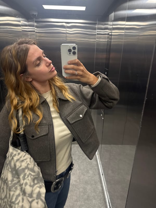 Woman takes elevator mirror selfie with silver iPhone