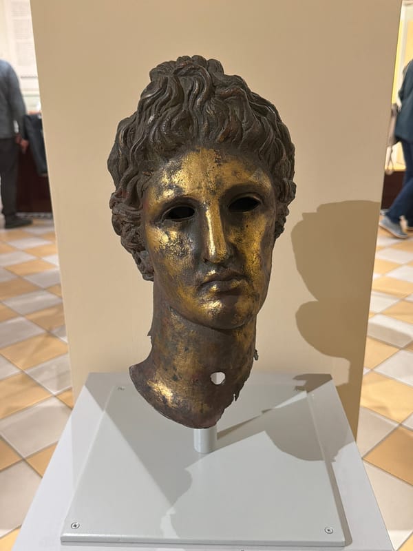 Museum visitor documents bronze sculpture and ancient dwelling exhibits
