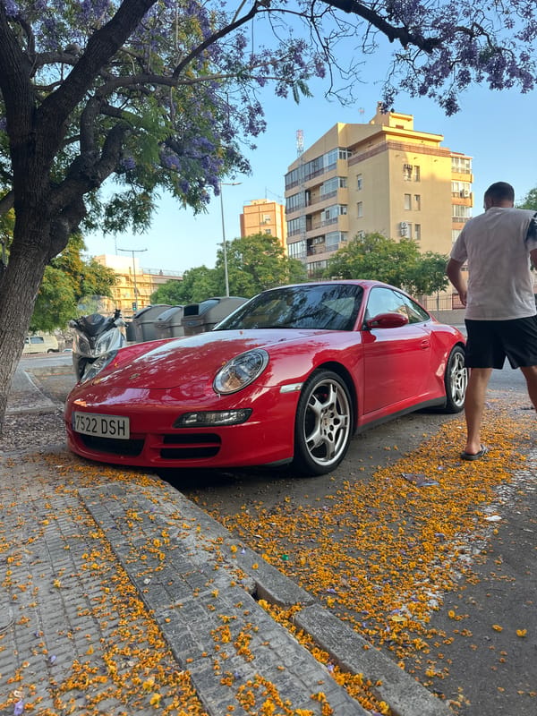 Man stands by red sports car on street