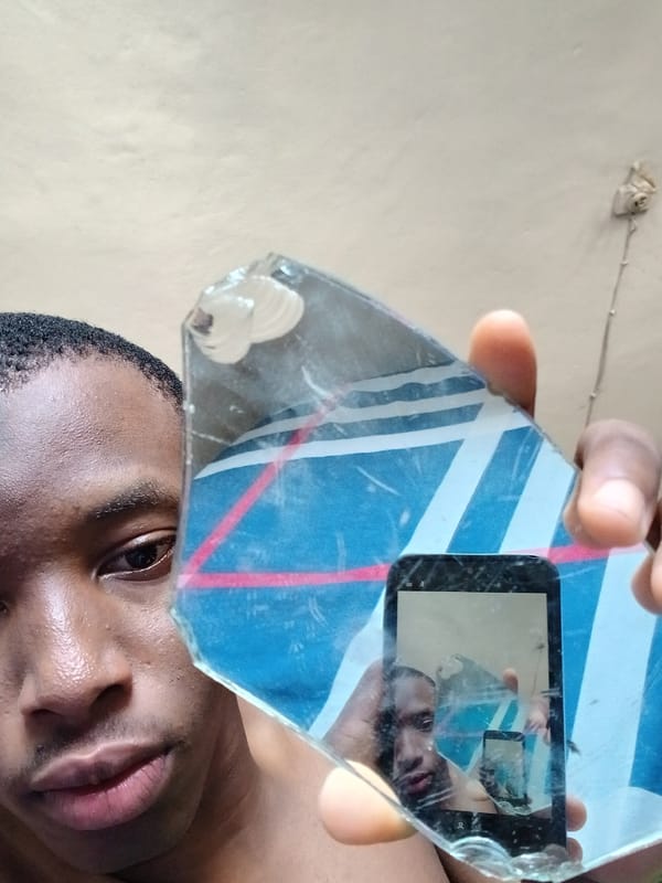 Person holds broken mirror fragment creating phone reflection in Lagos