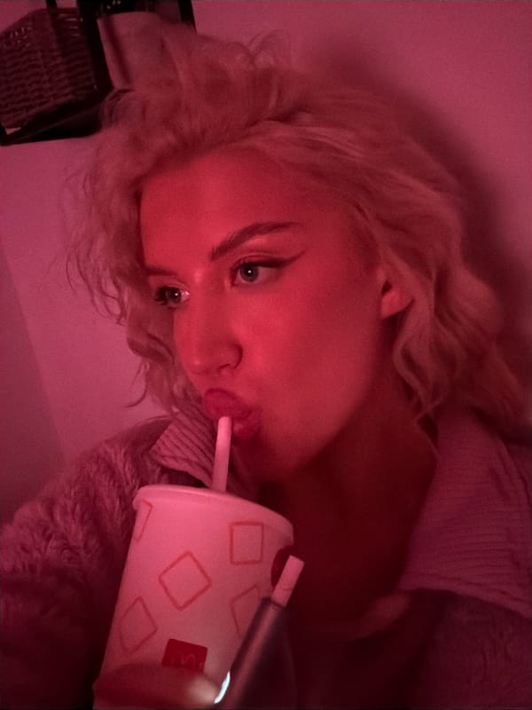 Person drinks McDonald's under pink lighting in Belgrade