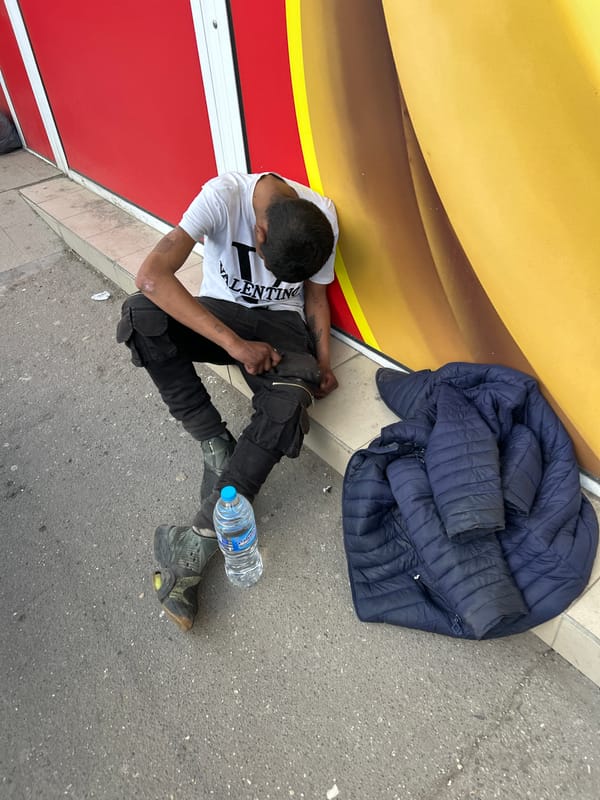 Man sits on Sofia sidewalk wearing Valentino shirt
