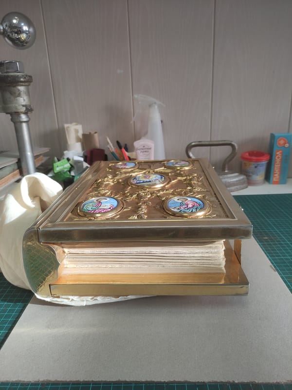 Ornate golden book cover documented in Moscow restoration workshop