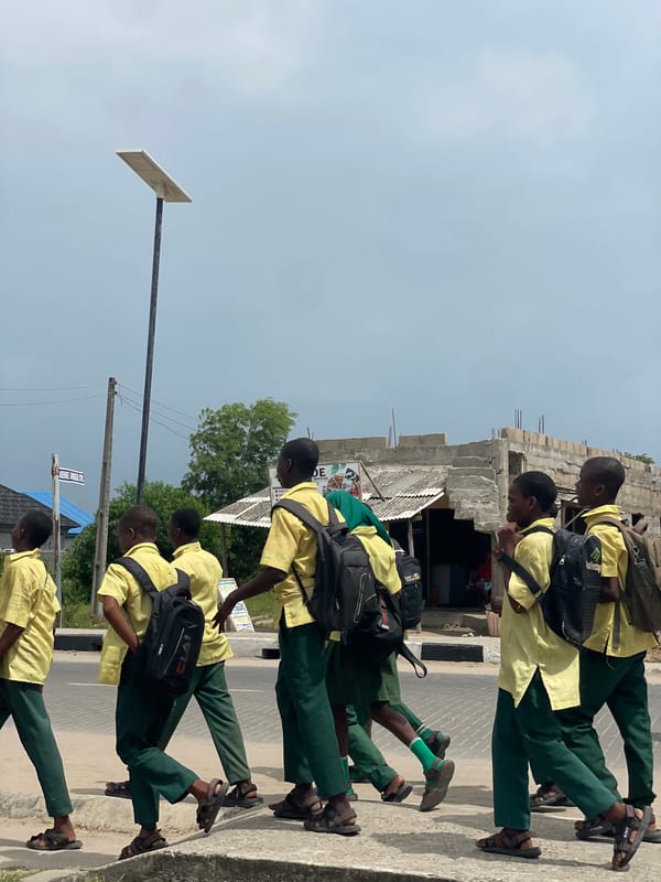 School children walk streets as motorcycle passes in Badagry