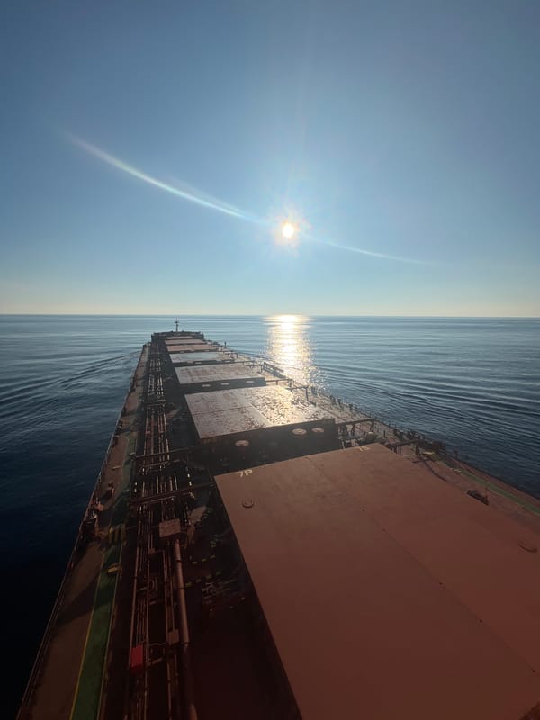 Cargo ship crossing open ocean under a high midday sun