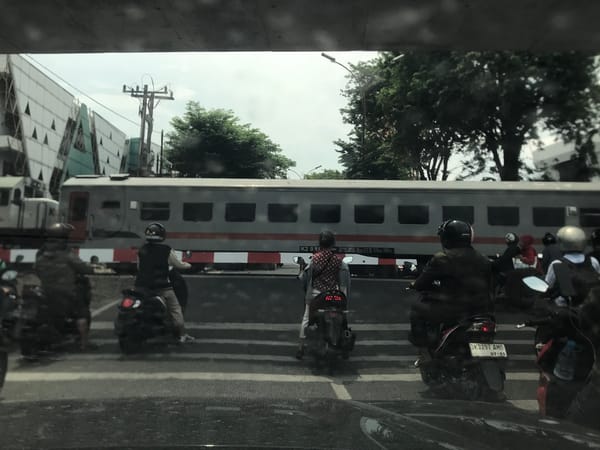 Motorbikes wait at crossing as train passes through Medan