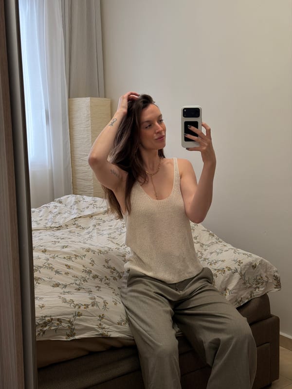 Woman takes mirror selfie on bed in Budva