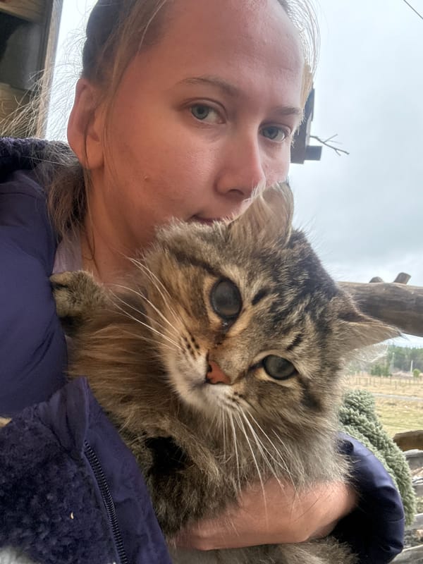 Woman takes selfie with cat, dog rests nearby in Tyulyuk
