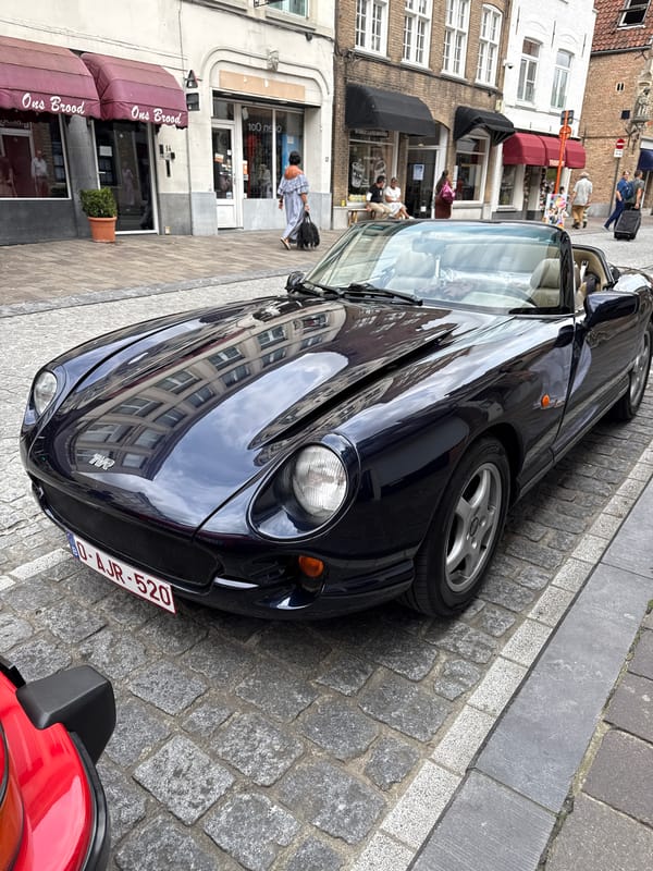 Classic sports cars parked on cobblestones in central Bruges