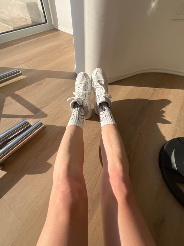 Person exercises in rainbow-lit gym wearing cartoon socks in Budva