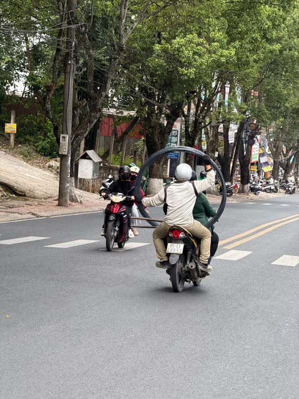 Motorcyclist carries large metal ring through Đà Lạt streets