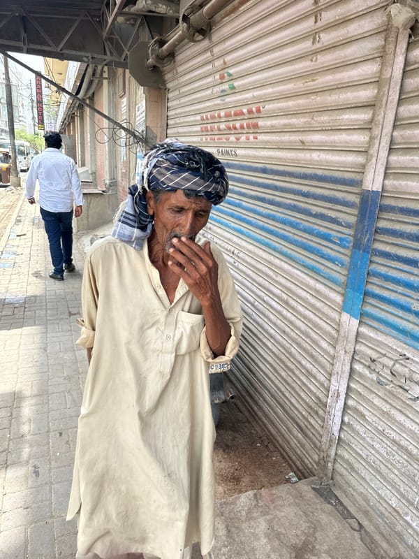 Morning street activity near a Karachi storefront, donkey cart in tow