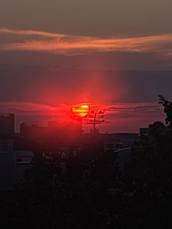 City skyline glows under a vivid orange and red sunset
