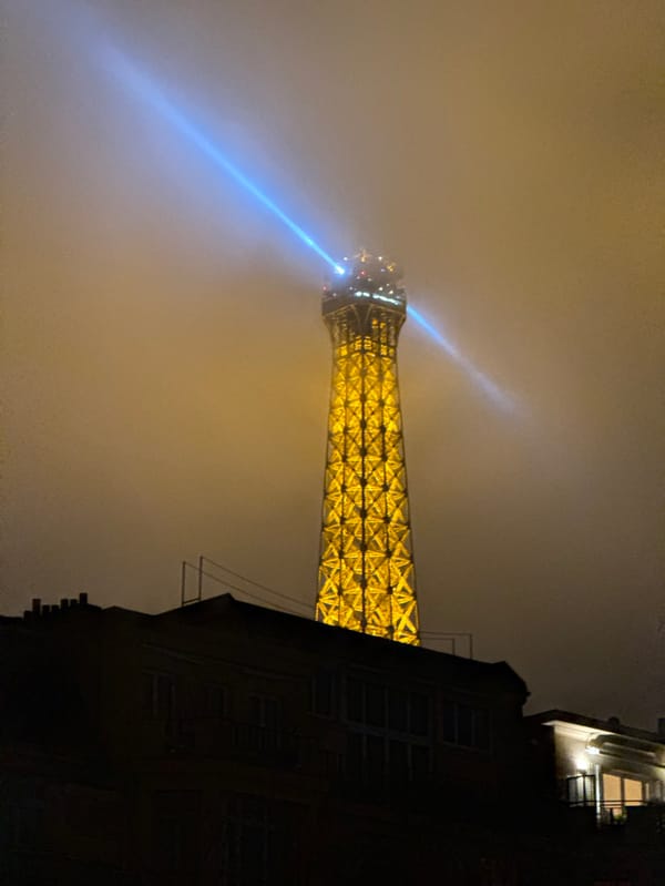 Eiffel Tower glows yellow through thick fog, Paris evening