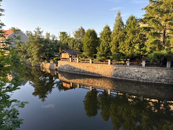 Still water and stone walls in golden afternoon light, Beroun