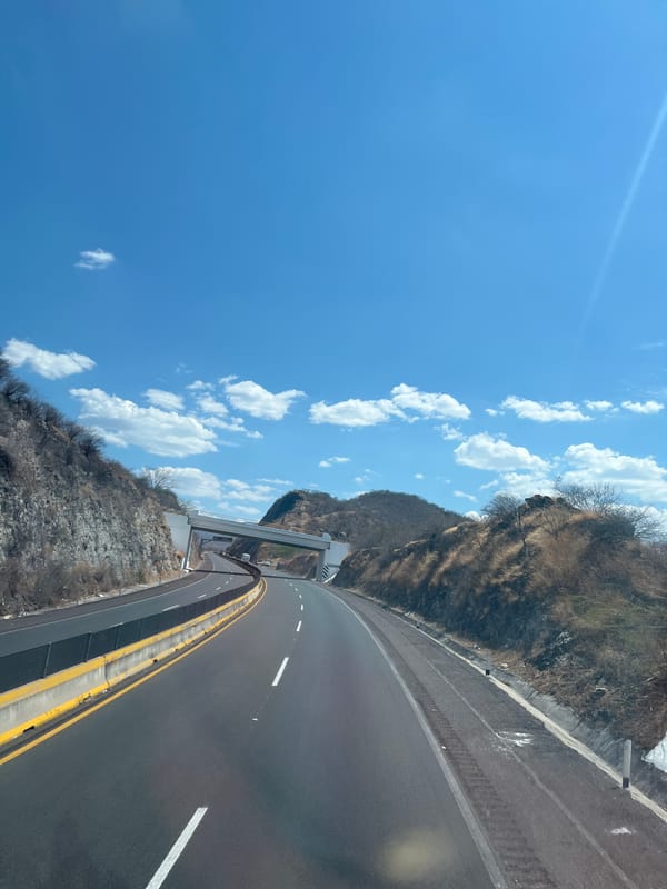 Highway curves through hilly Mexican terrain under blue skies