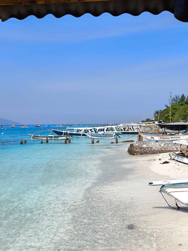 Peaceful Indonesian beach scene captured with boats visible offshore