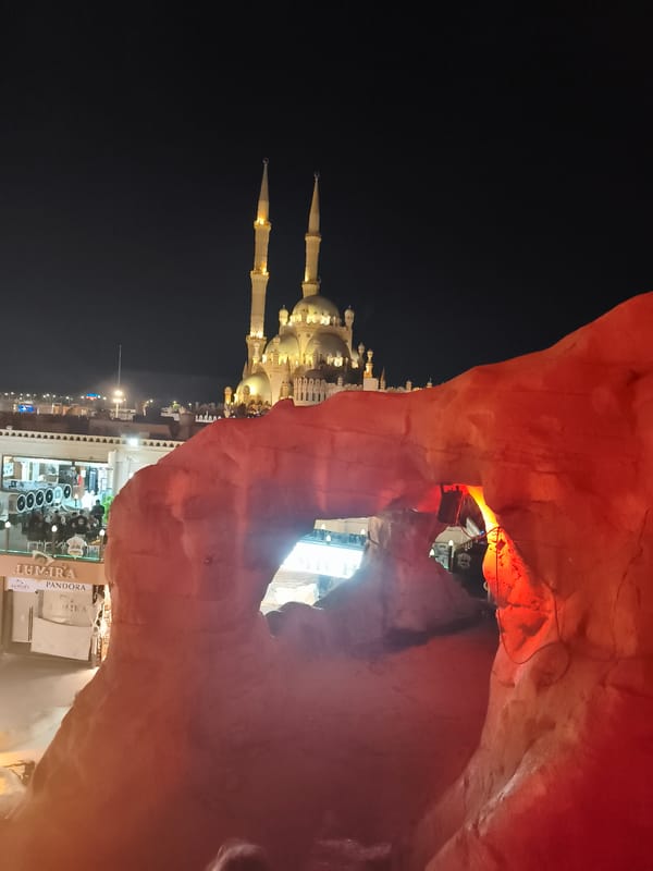 Naama Bay at night: mosque, markets, and cave venues