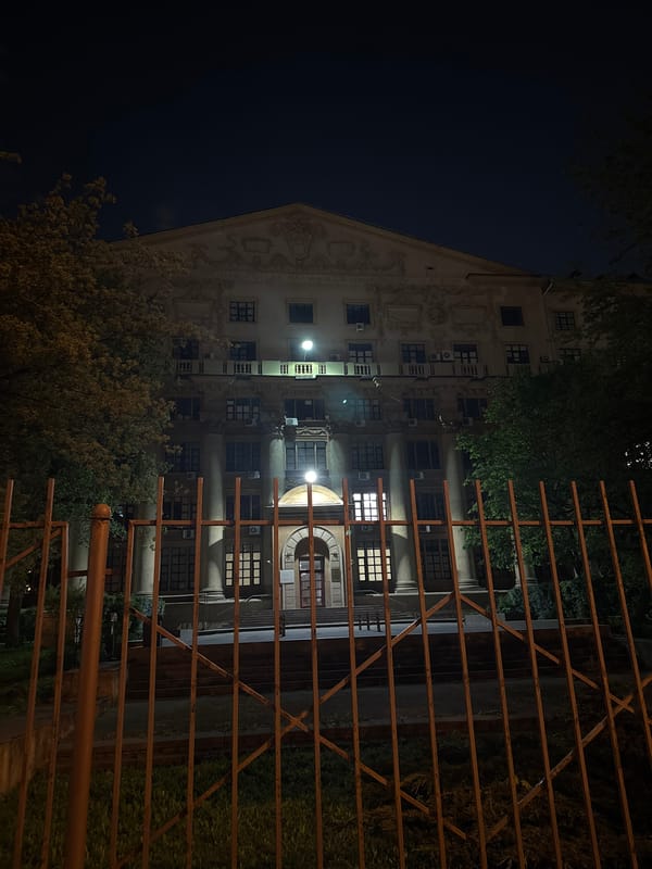 Man poses with outstretched arms near gated Moscow building