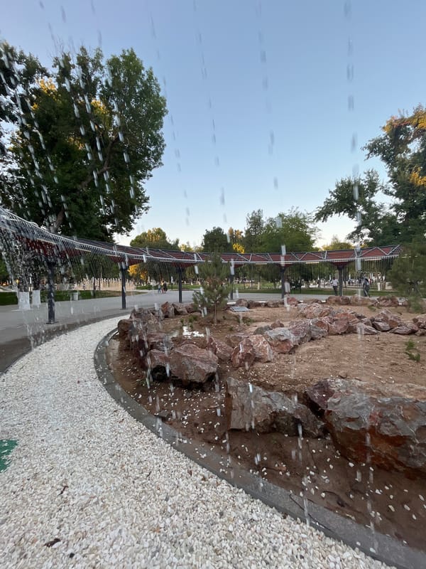 Shymkent park fountain and gravel paths on a wet afternoon