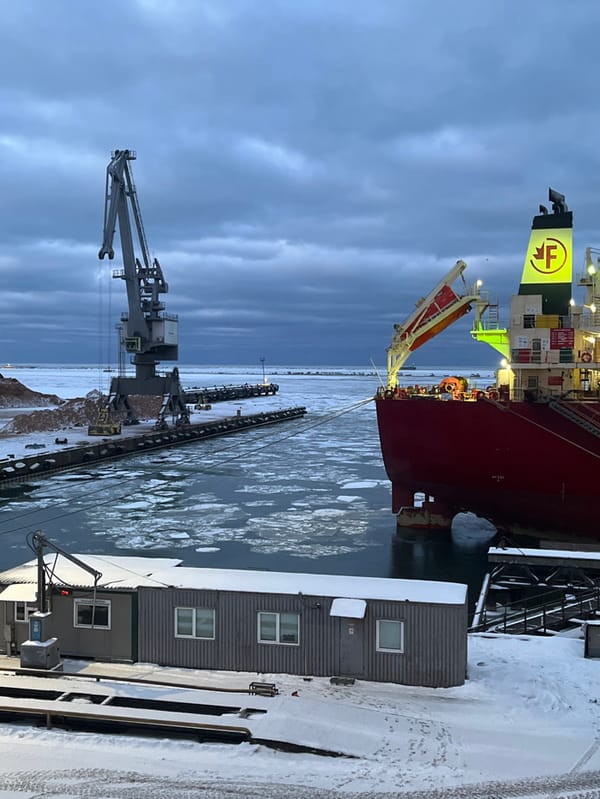 Red cargo ship docked at icy Liepaja port