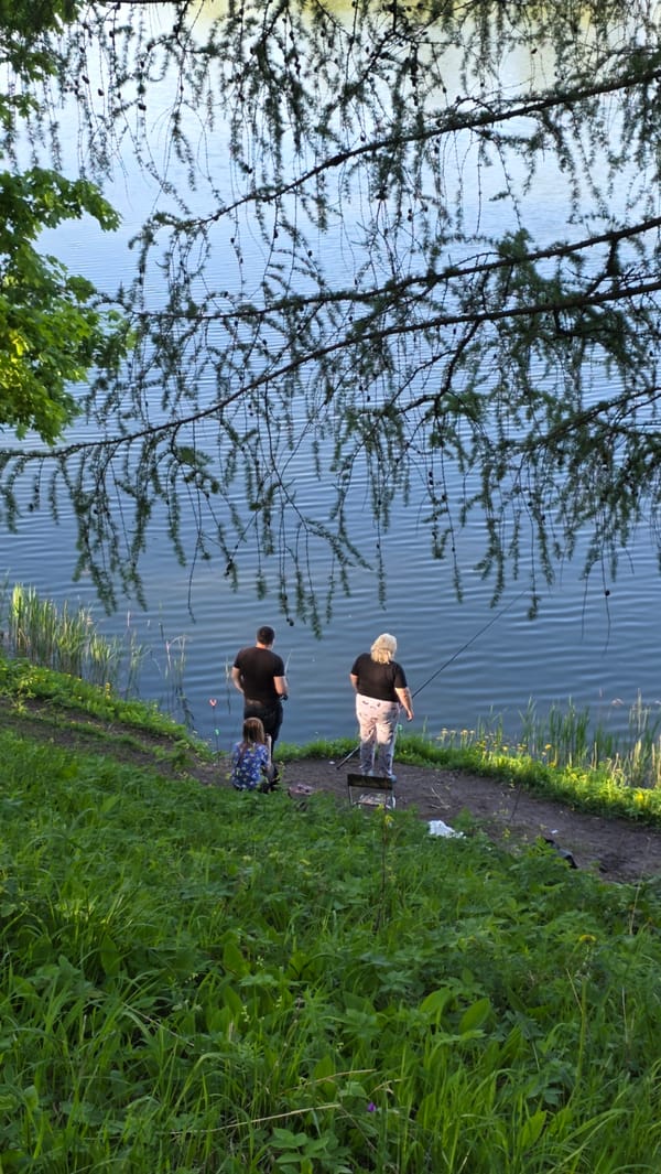 Two people fish along tranquil waterway in Gatchina, Russia