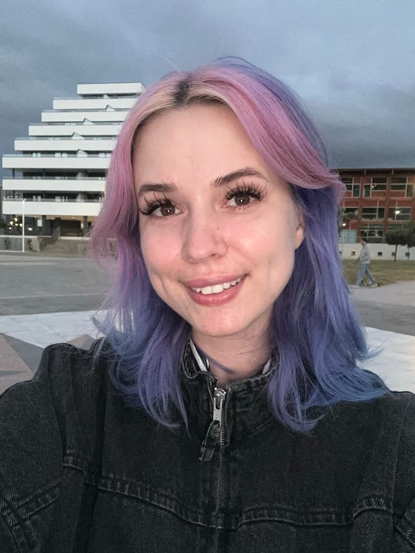 Young woman photographs herself at Gijón waterfront during golden hour