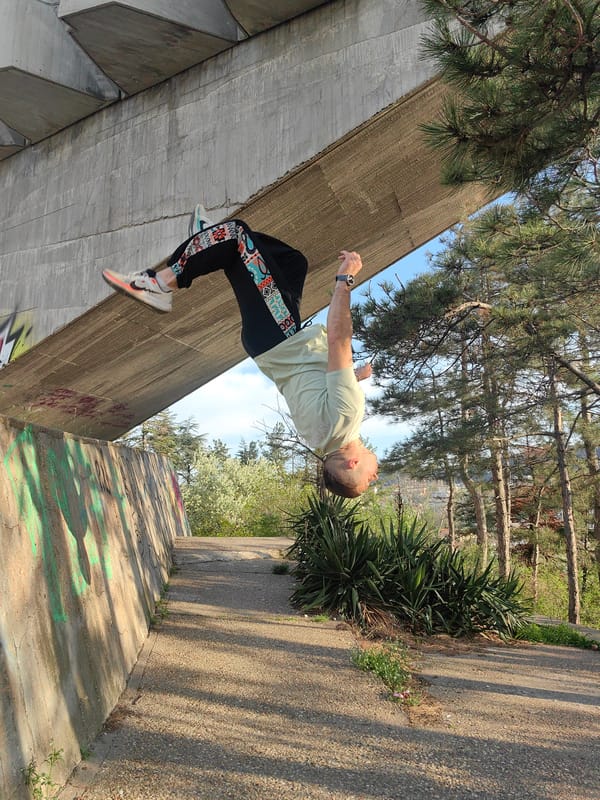 Man performs upside-down parkour move under concrete bridge