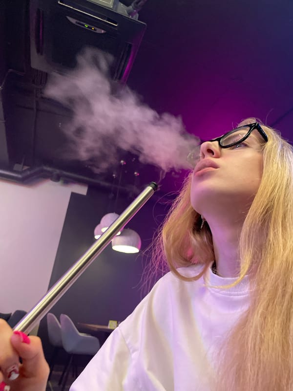Woman smoking hookah observed in Izhevsk under purple lighting