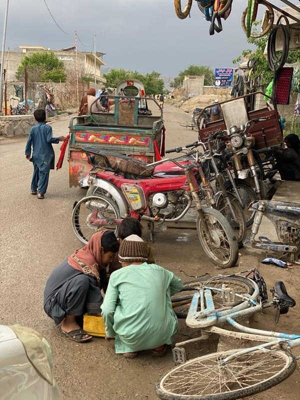 Children repair damaged bicycle on Kandahar street