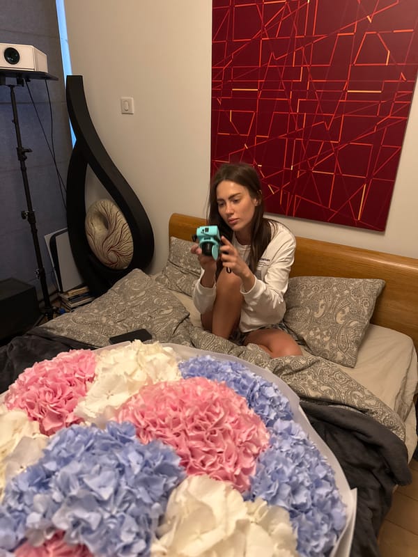 Woman takes instant camera selfies with flower bouquet in Warsaw