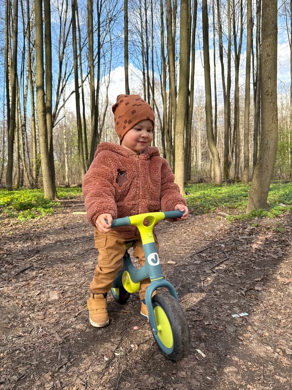 Child with balance bike spotted on wooded path in Rusanovo