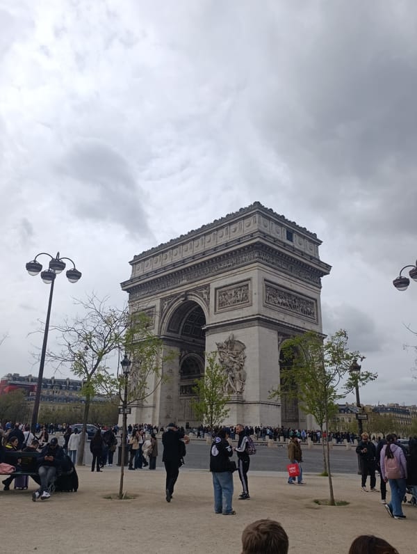 Tourists visit Arc de Triomphe under cloudy Paris skies