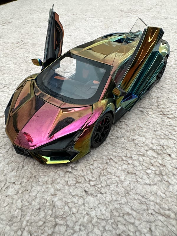 Multi-colored toy car with open door spotted on textured surface