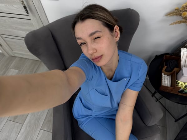 Woman takes selfie while reclining in gray armchair