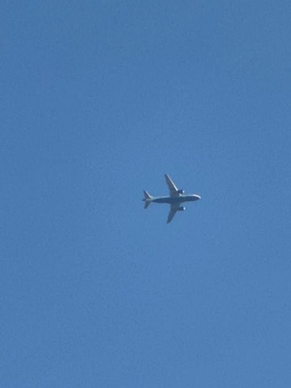 Orange-accented commercial jet cruises through clear London skies