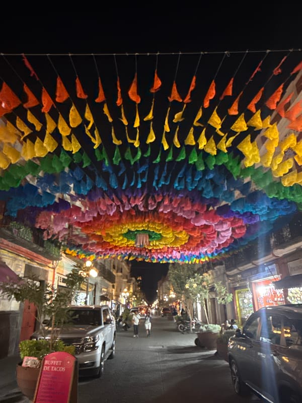 Colorful papel picado decorations illuminate Puebla street at night