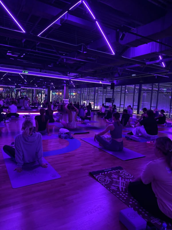 Large yoga class held in purple-lit Murino studio