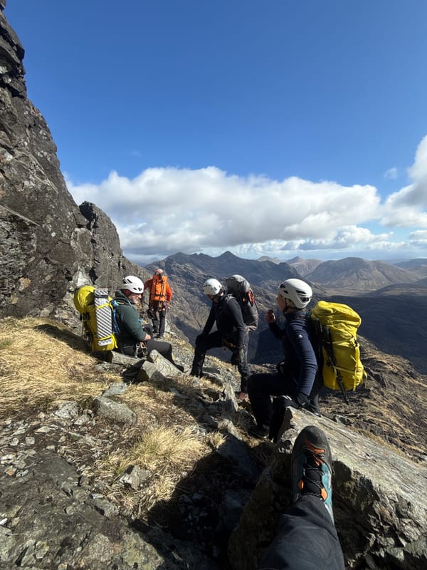 Helmeted hikers traverse rocky mountain ridge in formation