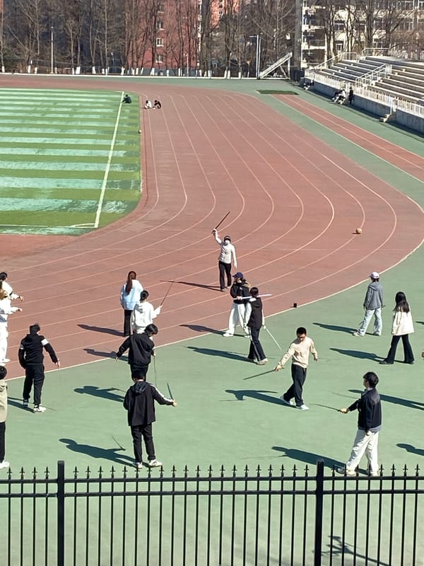 Group practices martial arts, fencing at Chinese stadium