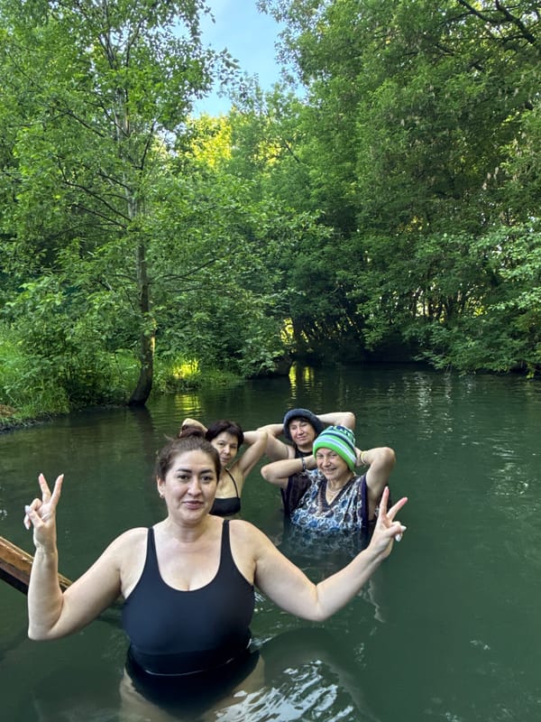 Group wades in green river near Kazan, one in a novelty hat