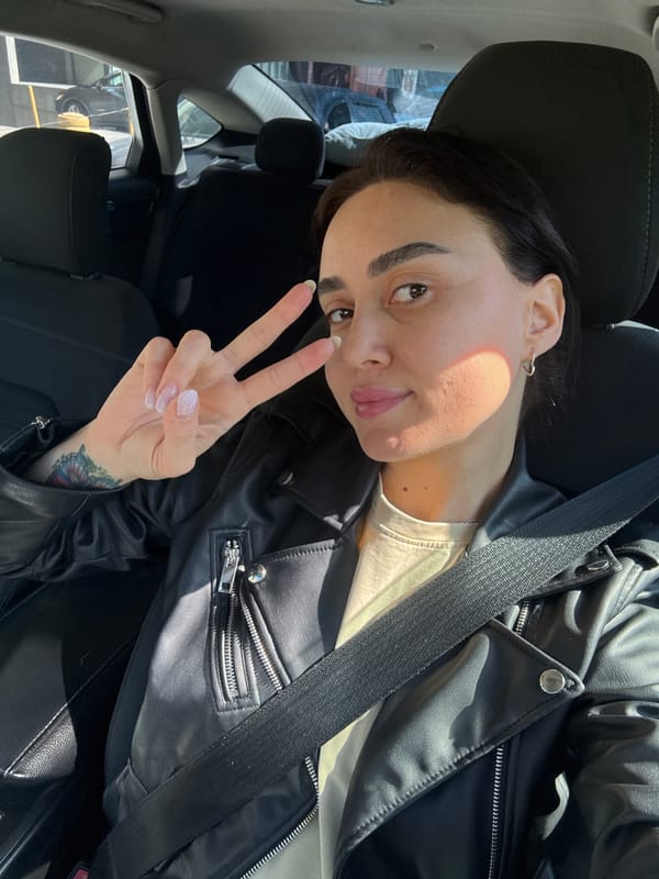 Woman makes peace sign while seated in car, Tbilisi