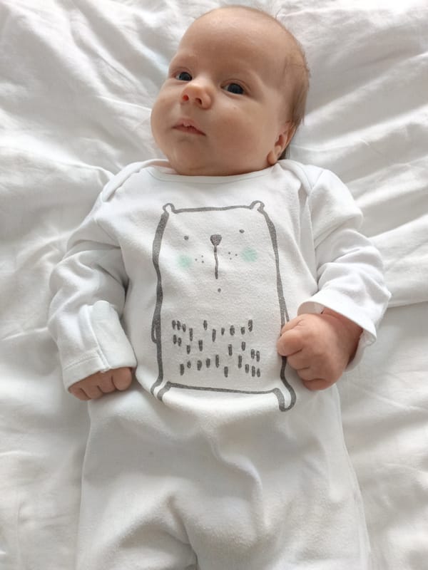 Newborn baby photographed in white onesie in Andreyevo, Russia