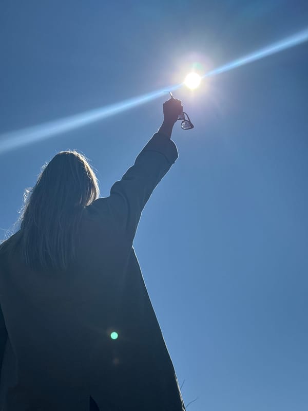 Person holds glasses to sun in Chaikovsky morning sky