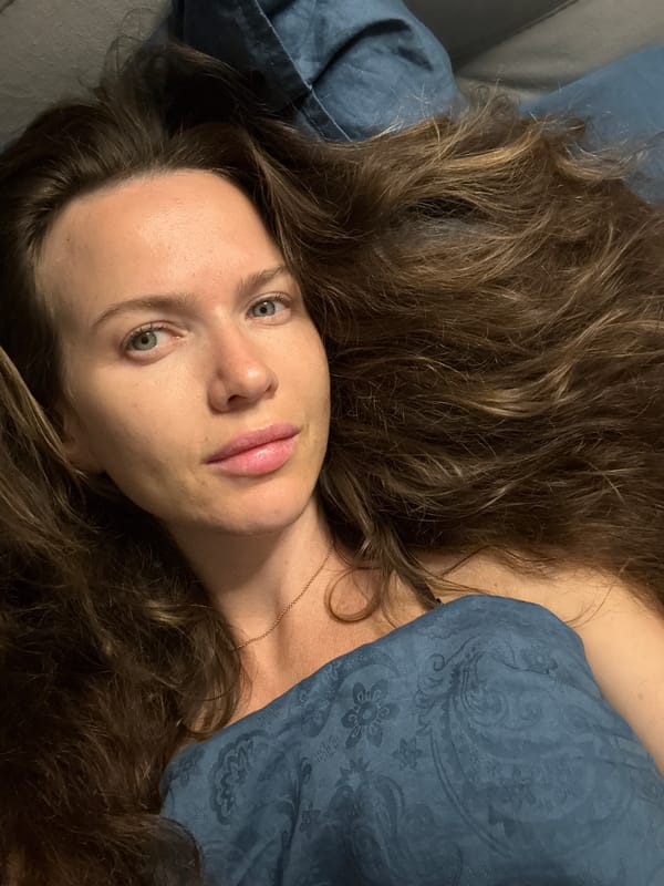 Relaxed moment in bed, blue bedding, direct gaze at camera