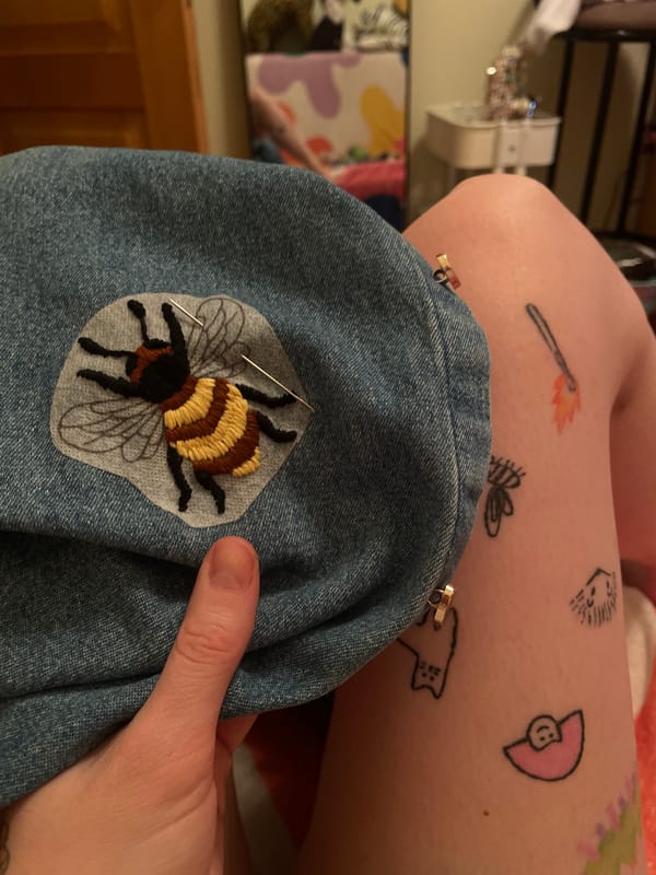 Person crafts embroidery on denim garment in Belgrade indoor setting